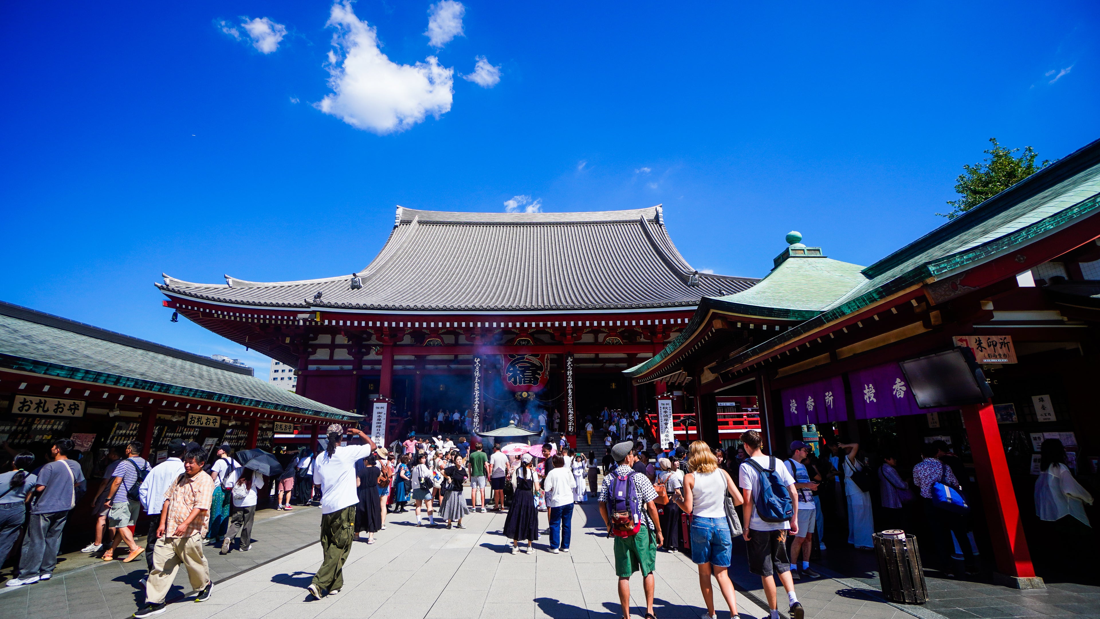 People visiting Senso Ji temple on a sunny day with blue sky.